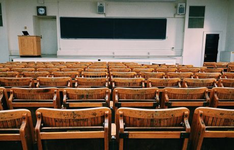 classroom lecture style room with chairs facing screen and podium